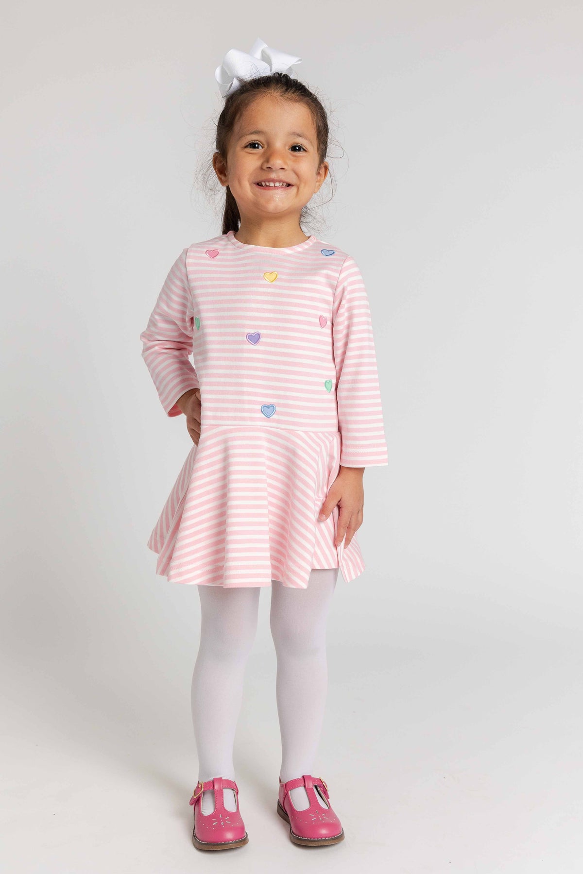 Young girl wearing a pink dress with heart patterns on a white background