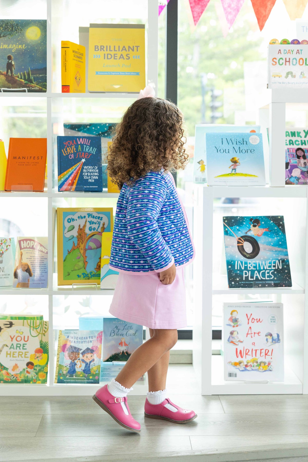 Child standing in front of a bookshelf filled with colorful books