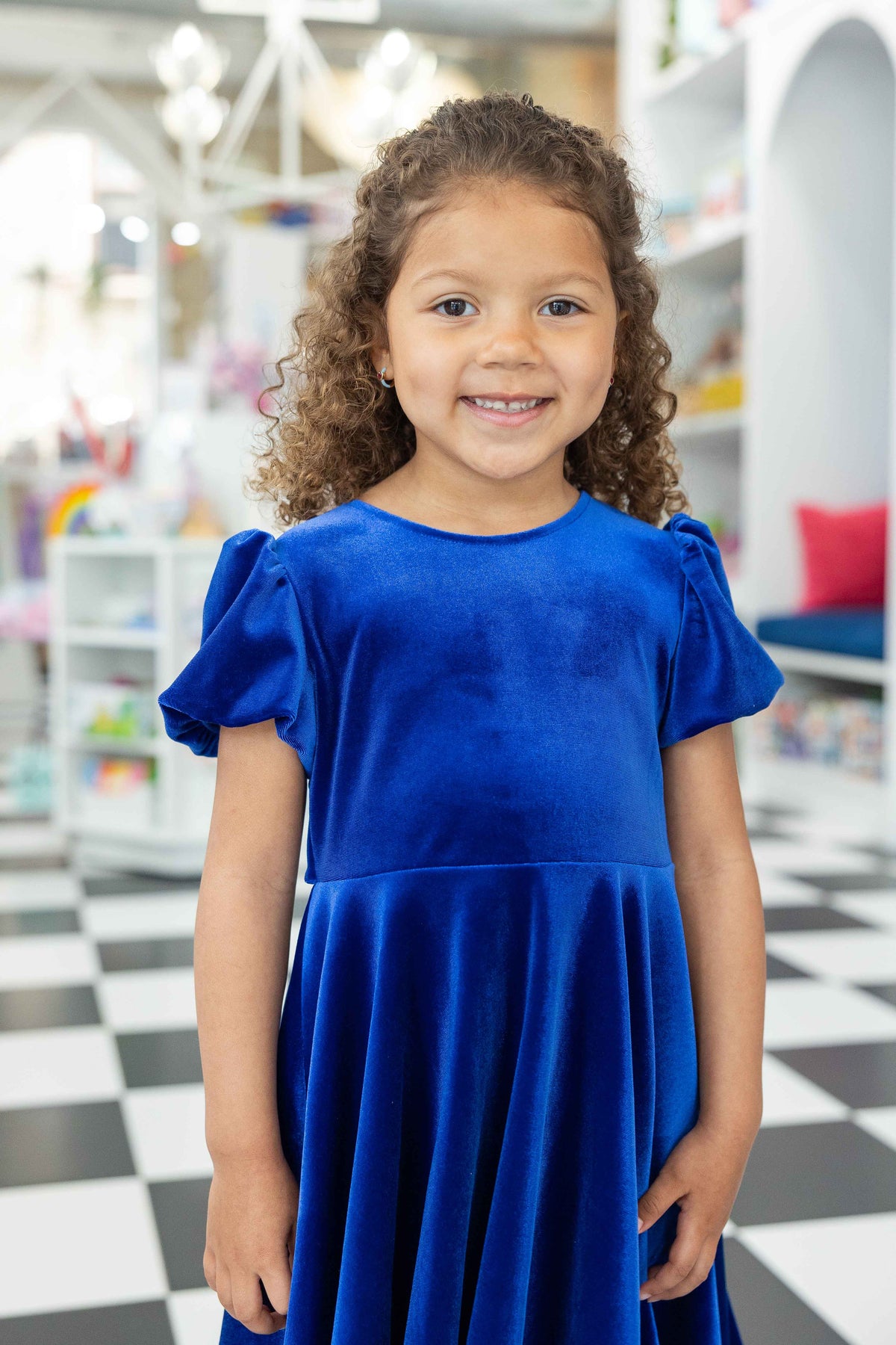 Young girl wearing a blue dress in a store setting