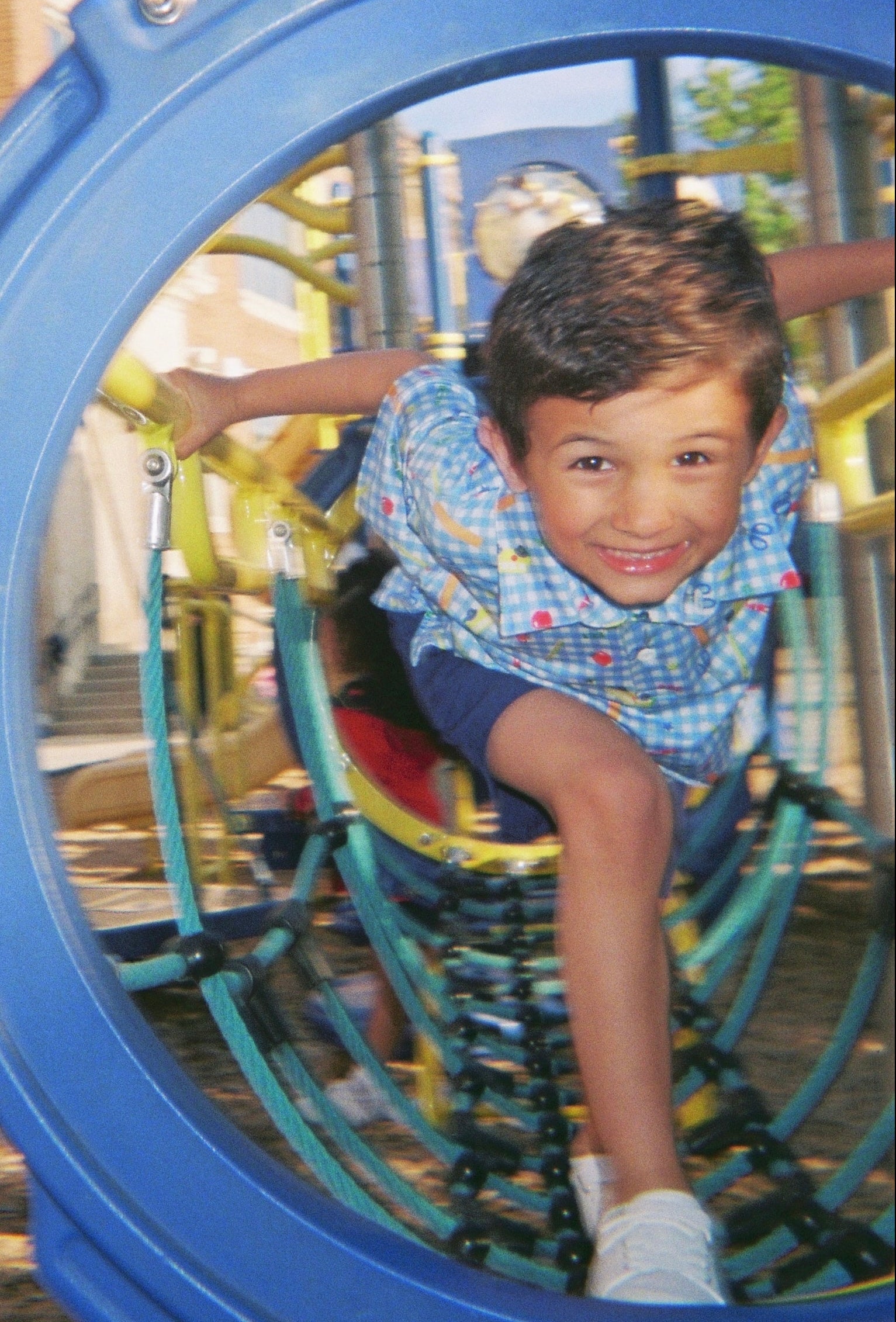 Child playing on a playground structure with a blue circular frame.