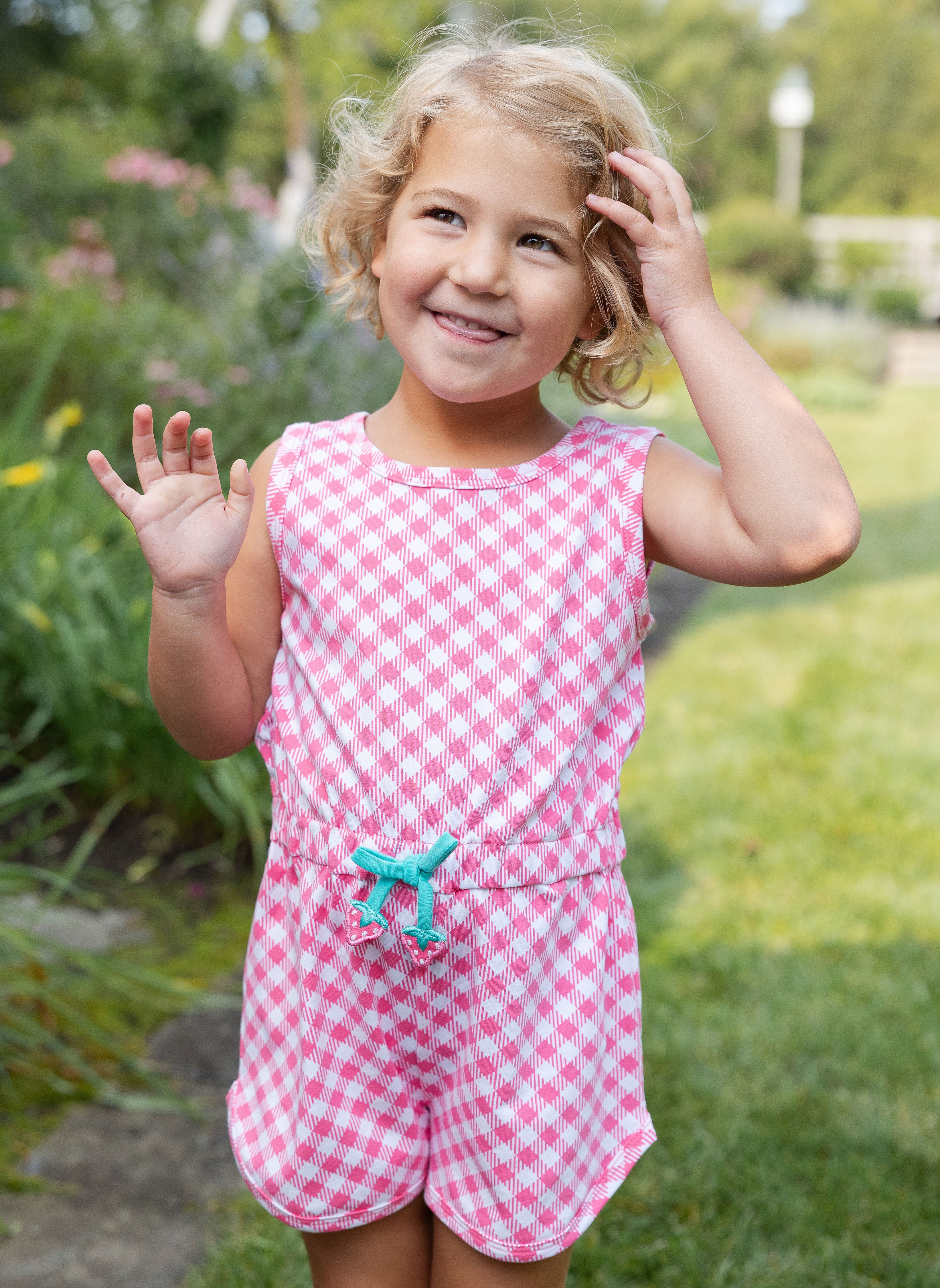 young girl in pink gingham jumper with strawberry waist ties