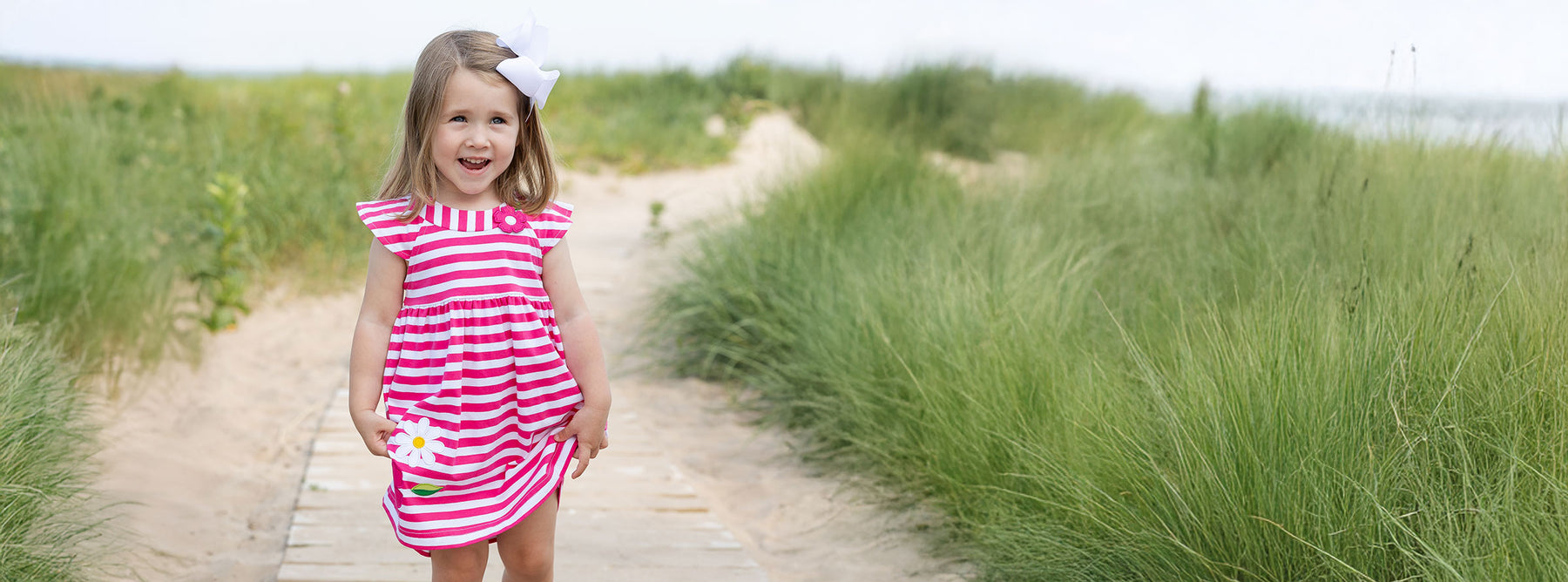 young girl on boardwalk in fuschia and white stripe dress