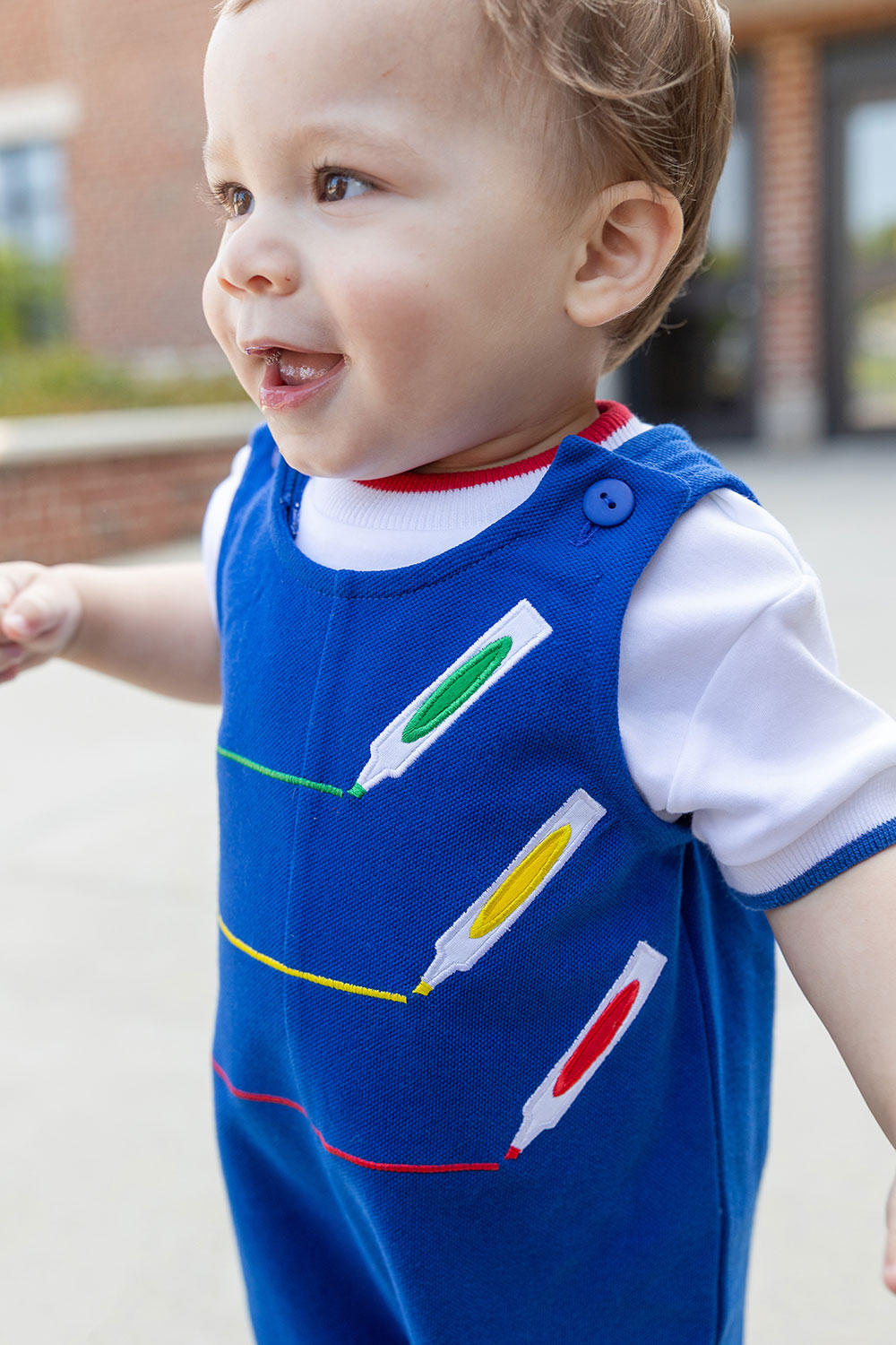Child wearing a blue outfit with colorful designs outdoors