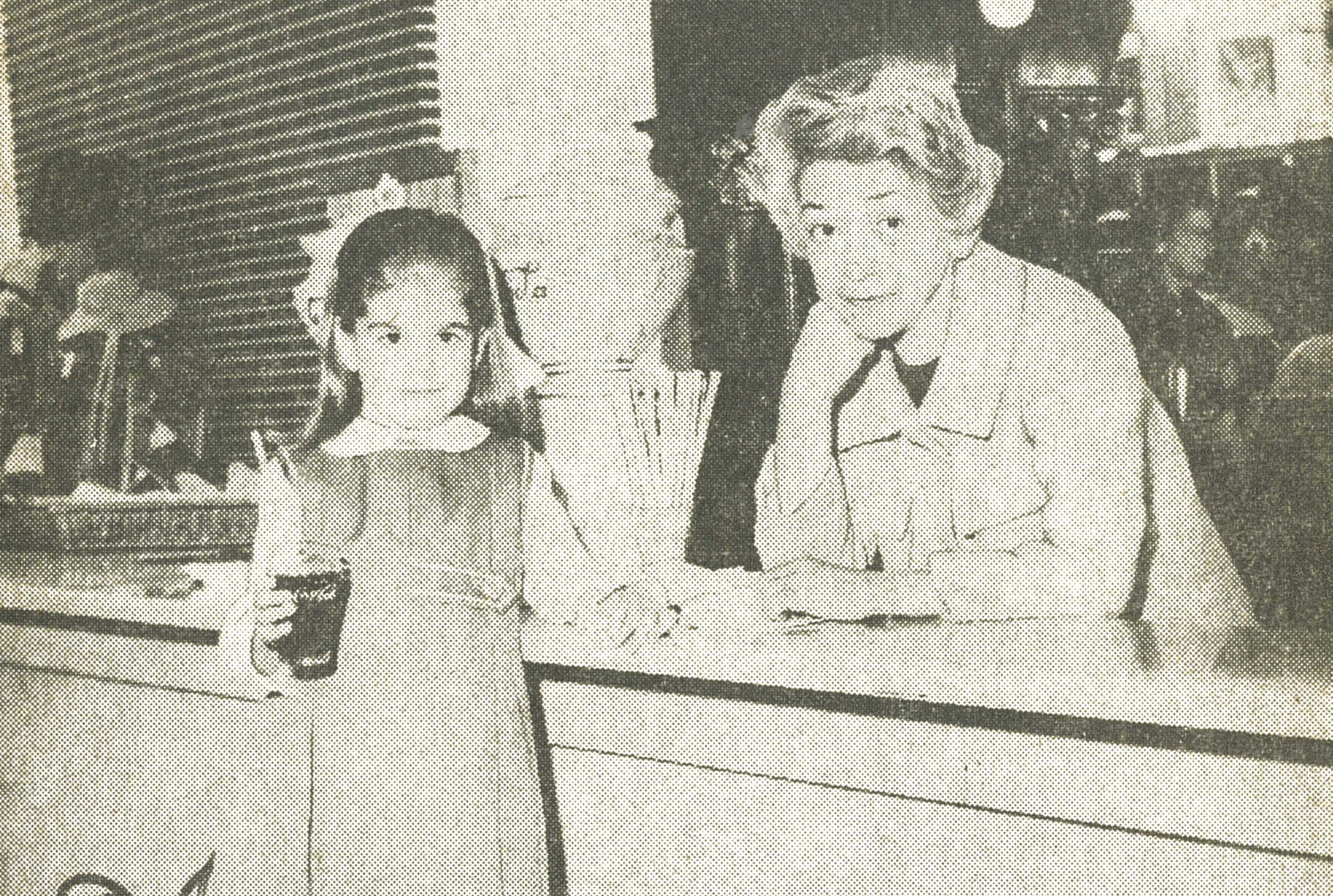 Black and white photo of a young girl and an Florence Eiseman at a soda stand.