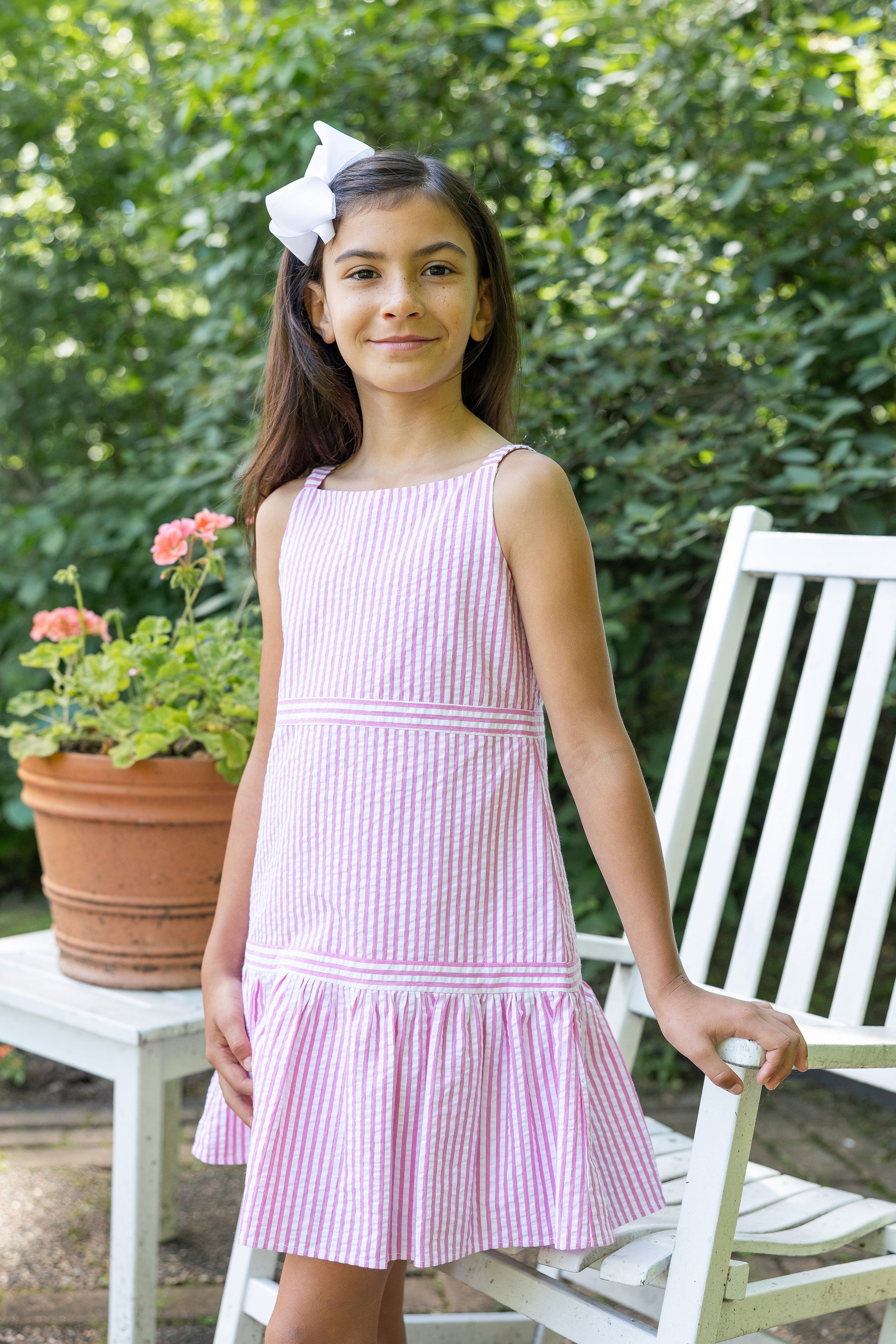 Girl standing in front of garden chair in pink stripe seersucker dress